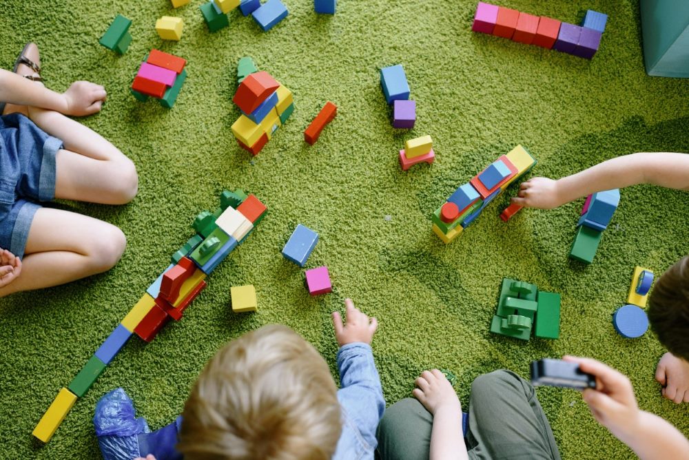 A group of children are playing with coloured wooden blocks