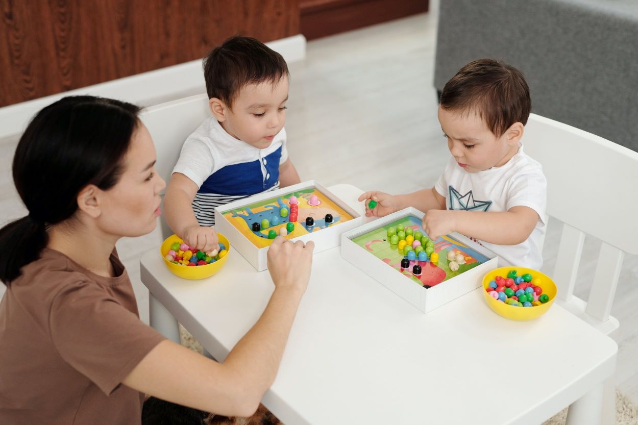 Two toddlers are playing with their mother